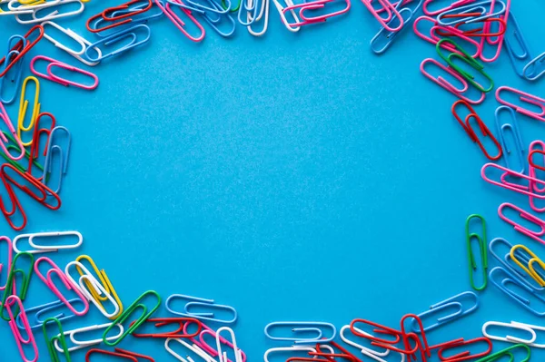 Vue de dessus du cadre avec trombones colorés sur bleu — Photo de stock