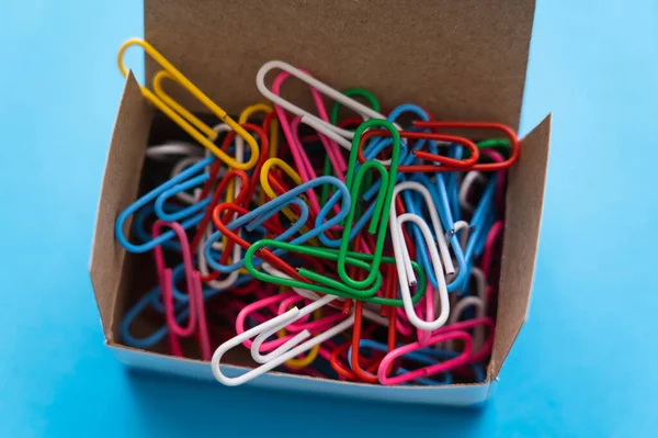 Close up view of box with colorful paper clips on blue — Fotografia de Stock