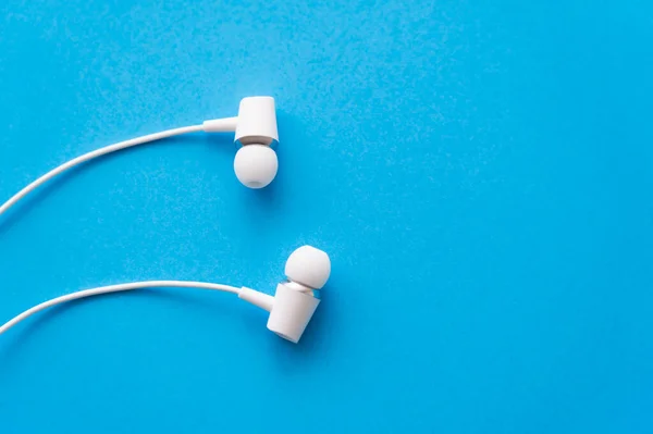 Top view of wired earphones on blue background - foto de stock