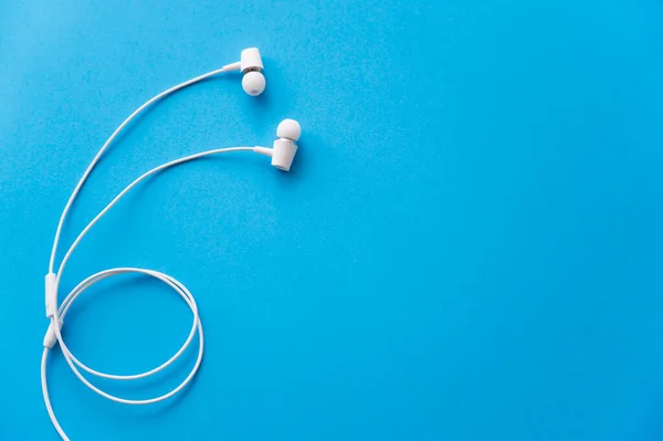 Top view of white wired earphones on blue — Stockfoto