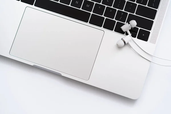 Вид зверху на білі дротяні навушники біля ноутбука на білому — стокове фото