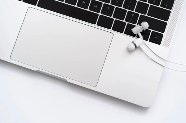 Vista superior de auriculares con cable blanco cerca de la computadora portátil en blanco - foto de stock