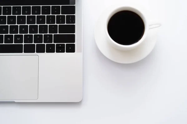 Vista dall'alto di tazza di caffè vicino a computer portatile su bianco — Foto stock