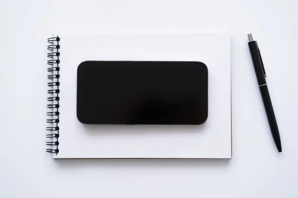 Vista superior do smartphone com tela em branco no notebook perto da caneta no branco — Fotografia de Stock