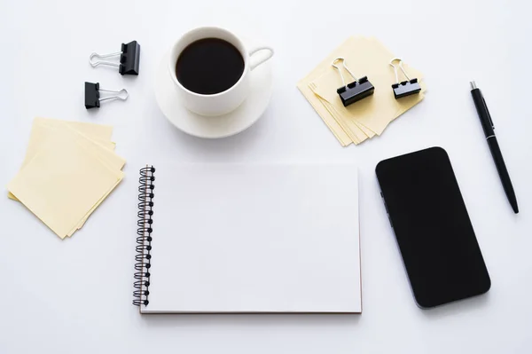Top view of smartphone with blank screen near cup of coffee and stationery on white — Stockfoto