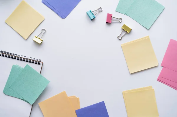 Flat lay of colorful paper notes and fold back clips on white — Stockfoto