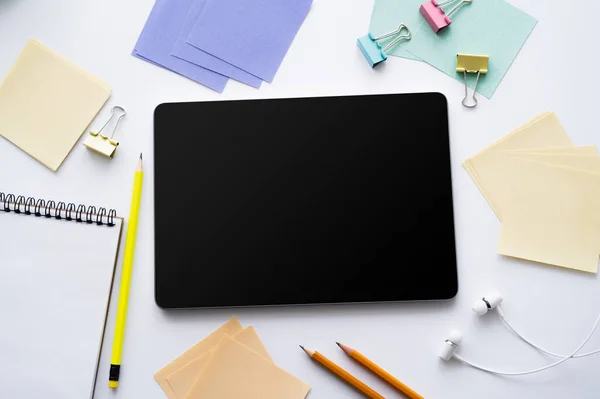 Top view of digital tablet with blank screen and earphones near stationery on white - foto de stock