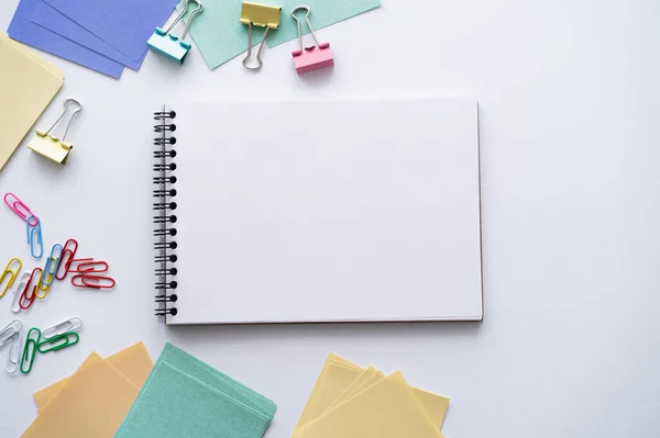 Vista superior del cuaderno en blanco cerca de papelería de colores en blanco - foto de stock