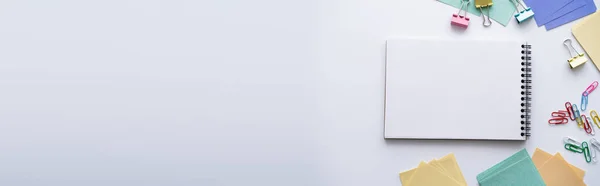 Vista dall'alto del taccuino bianco vicino alla cancelleria colorata su bianco, banner — Foto stock