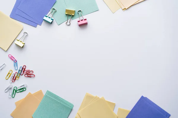 Top view of colorful fold back clips and paper notes on white — Stockfoto