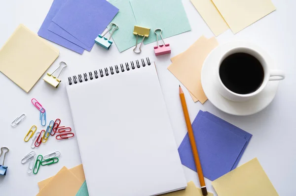 Draufsicht auf Kaffeebecher in der Nähe von leerem Notizbuch und Schreibwaren auf Weiß — Stockfoto