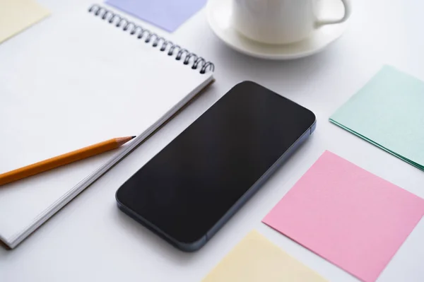 Close up of stationery near smartphone with blank screen on white — стоковое фото