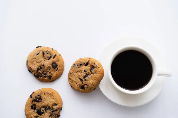 Vue du dessus de tasse de café près de biscuits aux pépites de chocolat sur blanc — Photo de stock