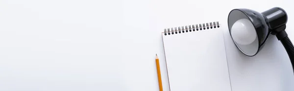 Top view of blank notebook near pencil and lamp on white, banner — Stock Photo