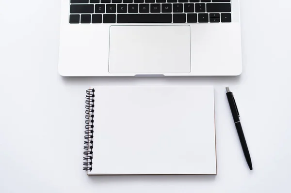 Top view of notebook and pen near modern laptop on white — Photo de stock