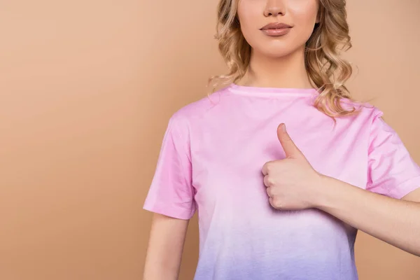 Частичный вид молодой женщины в футболке, показывающей большой палец, изолированный на бежевом — стоковое фото
