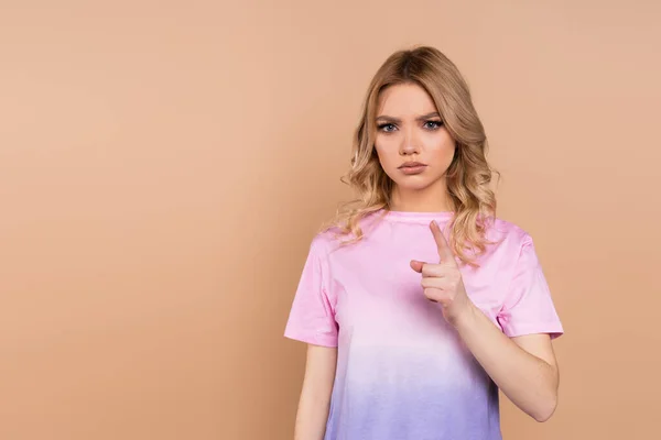 Strict woman in t-shirt pointing with finger at camera isolated on beige — Stockfoto