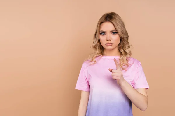 Strict woman in t-shirt pointing with finger at camera isolated on beige — стоковое фото