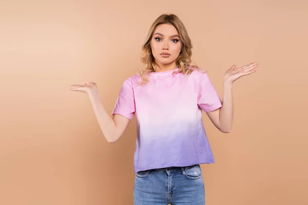 Confused woman showing shrug gesture and looking at camera isolated on beige — Stock Photo
