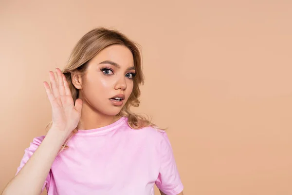 Pretty woman holding hand near ear isolated on beige — Stockfoto