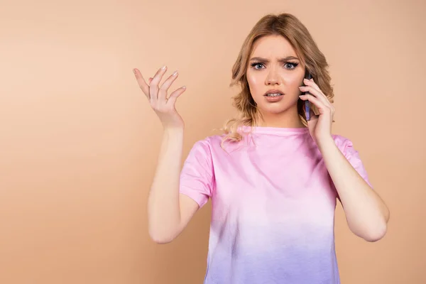 Displeased woman calling on smartphone and pointing with finger isolated on beige — Foto stock