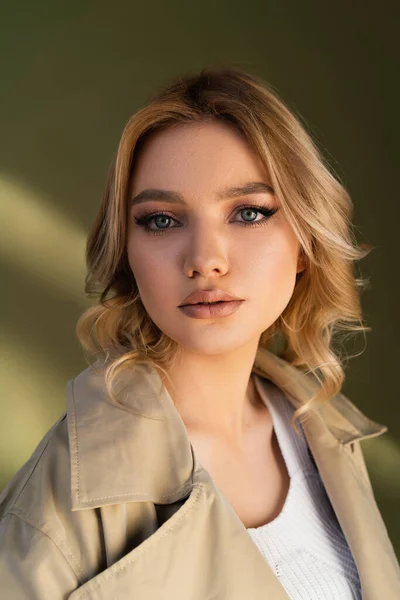 Retrato de mujer sensual joven con el pelo ondulado mirando a la cámara sobre fondo beige - foto de stock