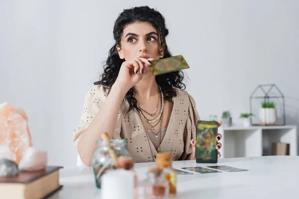 Pensive gypsy fortune teller holding tarot cards at home — стоковое фото