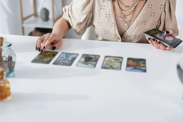 Vista recortada de adivino sosteniendo cartas del tarot en casa - foto de stock