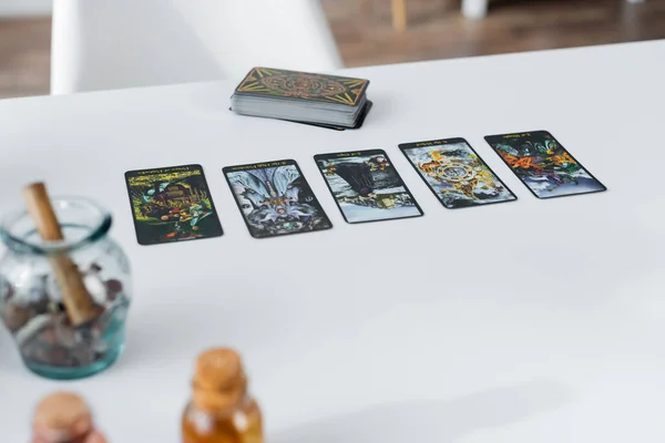 KYIV, UKRAINE - FEBRUARY 23, 2022: Tarot cards near blurred witchcraft supplies on table — Stock Photo