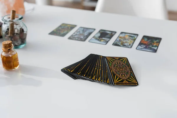 KYIV, UKRAINE - FEBRUARY 23, 2022: Tarot cards near jars with witchcraft supplies on table — Stock Photo