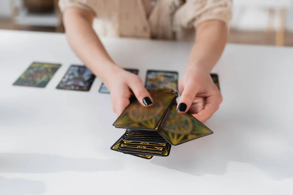 Cropped view of medium holding blurred tarot cards near table — Fotografia de Stock