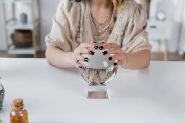 Ausgeschnittene Ansicht eines verschwommenen Mediums, das Glaskugel auf Tisch berührt — Stockfoto