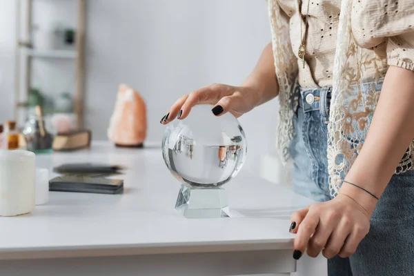 Cropped view of soothsayer touching orb near candles on table — стоковое фото