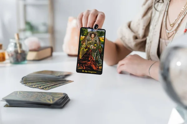 KYIV, UKRAINE - FEBRUARY 23, 2022: Cropped view of soothsayer holding tarot card at home — Photo de stock