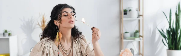 Gypsy fortune teller blowing on burning match near crystal at home, banner — Stock Photo