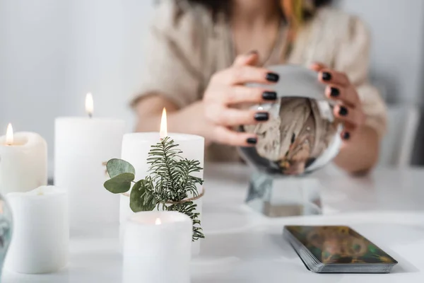 Vista recortada de velas ardientes cerca del tarot y medio borroso con orbe en casa — Stock Photo