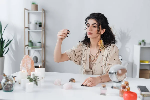 Gypsy fortune teller holding magic crystal near candles and magic orb at home - foto de stock