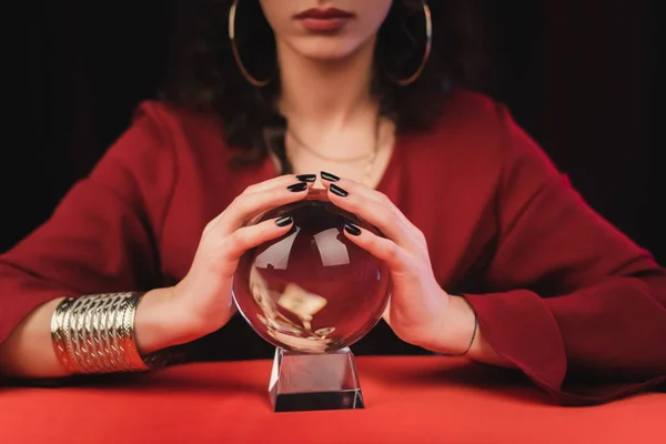 Cropped view of blurred medium touching magic orb isolated on black — Stock Photo