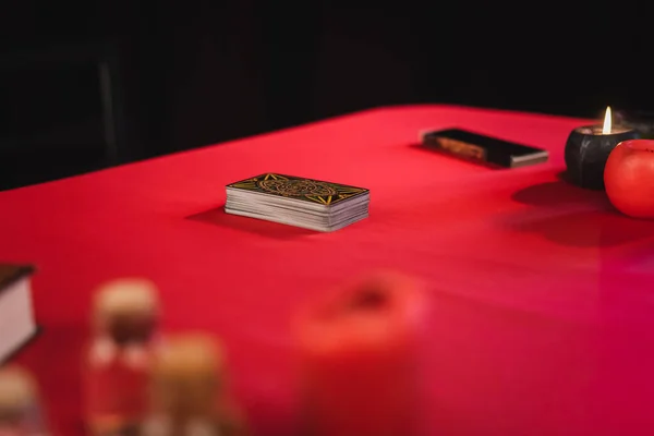 QUIIV, UCRÂNIA - FEVEREIRO 23, 2022: Cartas de tarô perto de velas e suprimentos de bruxaria borrada na mesa isolada em preto — Fotografia de Stock