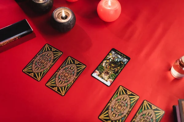 KYIV, UCRANIA - 23 de febrero de 2022: Vista superior de las cartas del tarot cerca de la quema de velas en la mesa - foto de stock