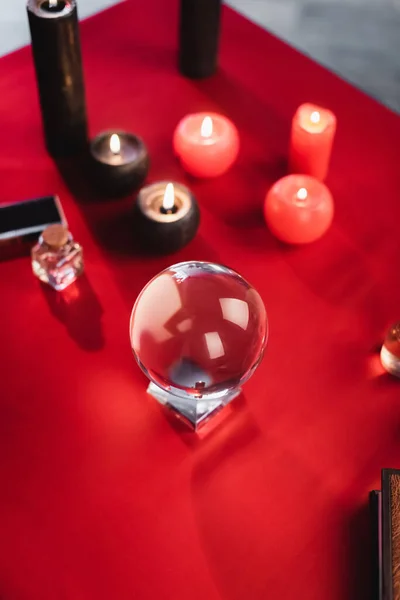 Top view of glass orb near blurred candles and book on table — Stock Photo