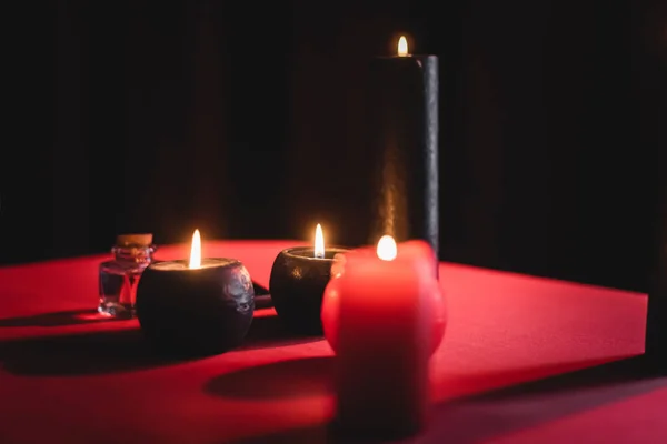 Burning candles and jar on table isolated on black — Stock Photo