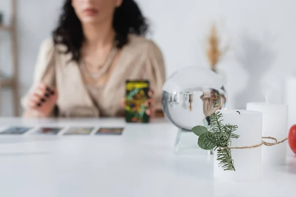 Vista recortada de velas y orbe cerca de adivino borrosa en casa — Stock Photo