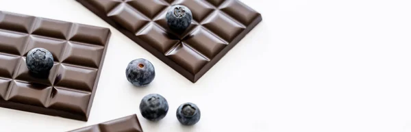 Close up view of fresh blueberries and chocolate bars on white background, banner — Stock Photo