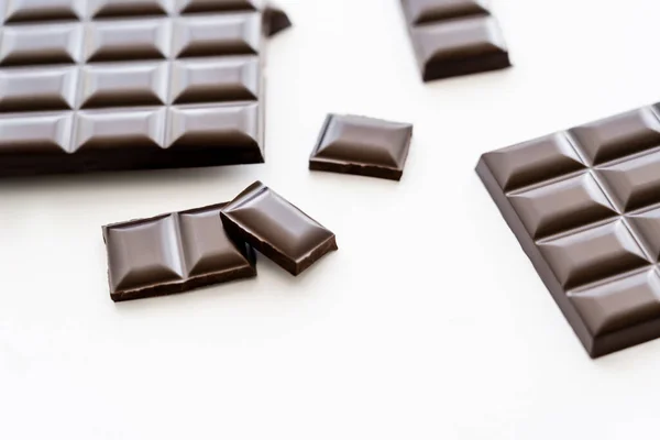Pieces and bars of brown chocolate on white background — Stockfoto