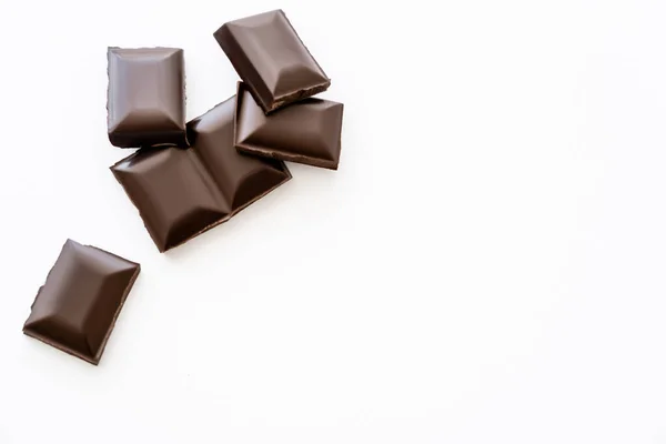 Vista superior de piezas de chocolate sobre fondo blanco con espacio para copiar - foto de stock