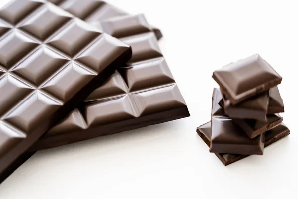 Close up view of bars and pieces of dark chocolate on white background — Photo de stock