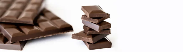 Vista de cerca de piezas de chocolate cerca de barras borrosas sobre fondo blanco, pancarta - foto de stock
