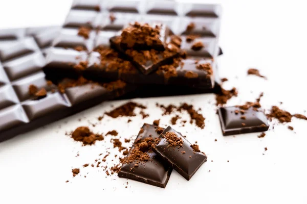 Vista da vicino di pezzi di cioccolato e cacao su sfondo bianco — Foto stock