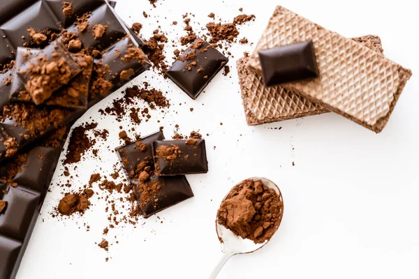 Vista superior de cacao en cuchara, barras de chocolate y gofres sobre fondo blanco - foto de stock